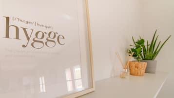 A framed sign with the word "hygg" and a definition, a potted plant, and a reed diffuser on a white surface.
