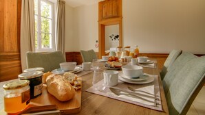 Una mesa de desayuno con pan, mantequilla y mermelada, con vistas al exterior a través de la ventana.