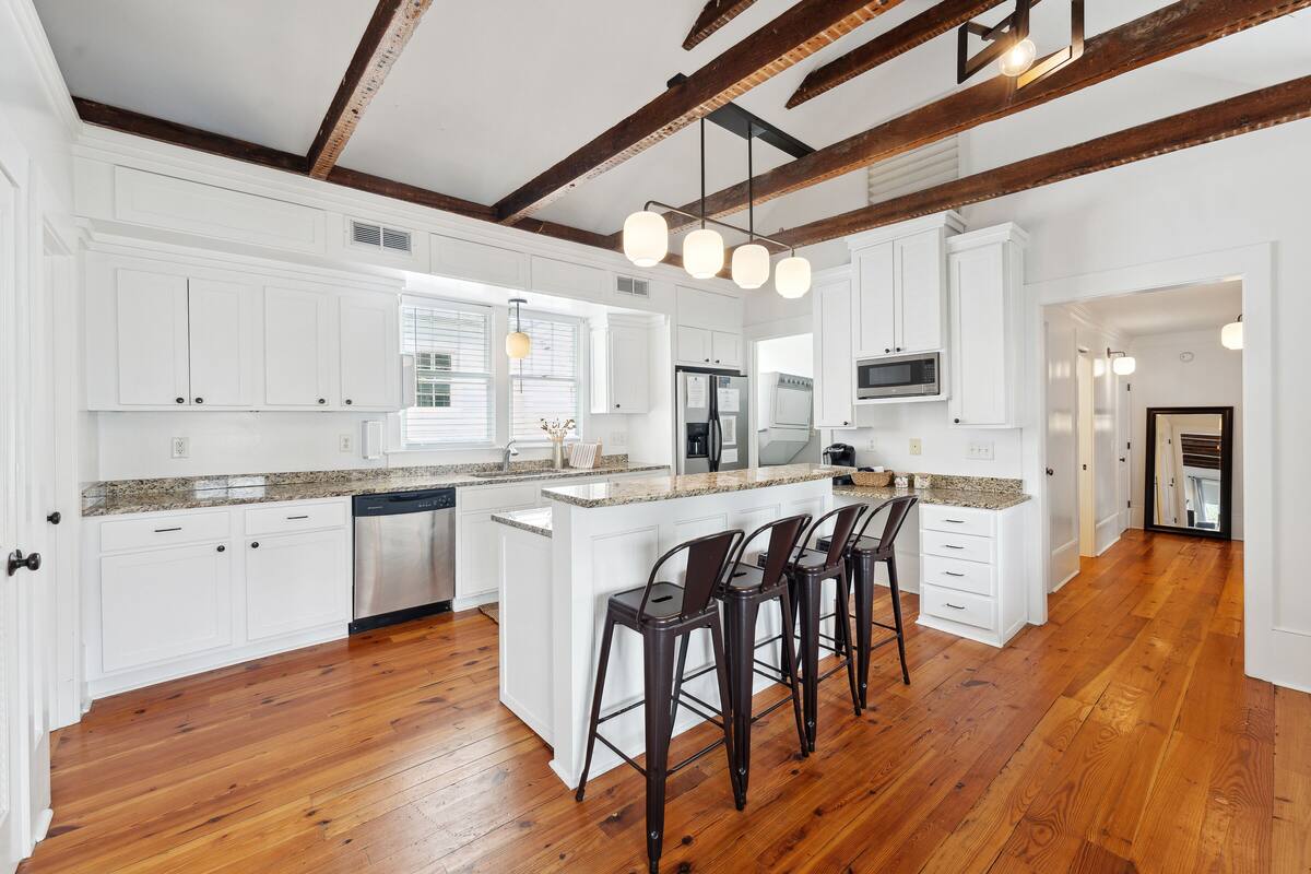 A spacious kitchen with white cabinetry, a granite countertop, and a central island with bar stools.