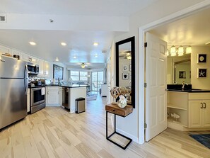 A modern kitchen with white cabinetry, stainless steel appliances, and a wooden dining area.