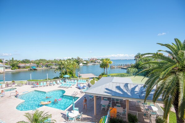 A resort pool area with multiple pools, lounge chairs, and a view of the water.