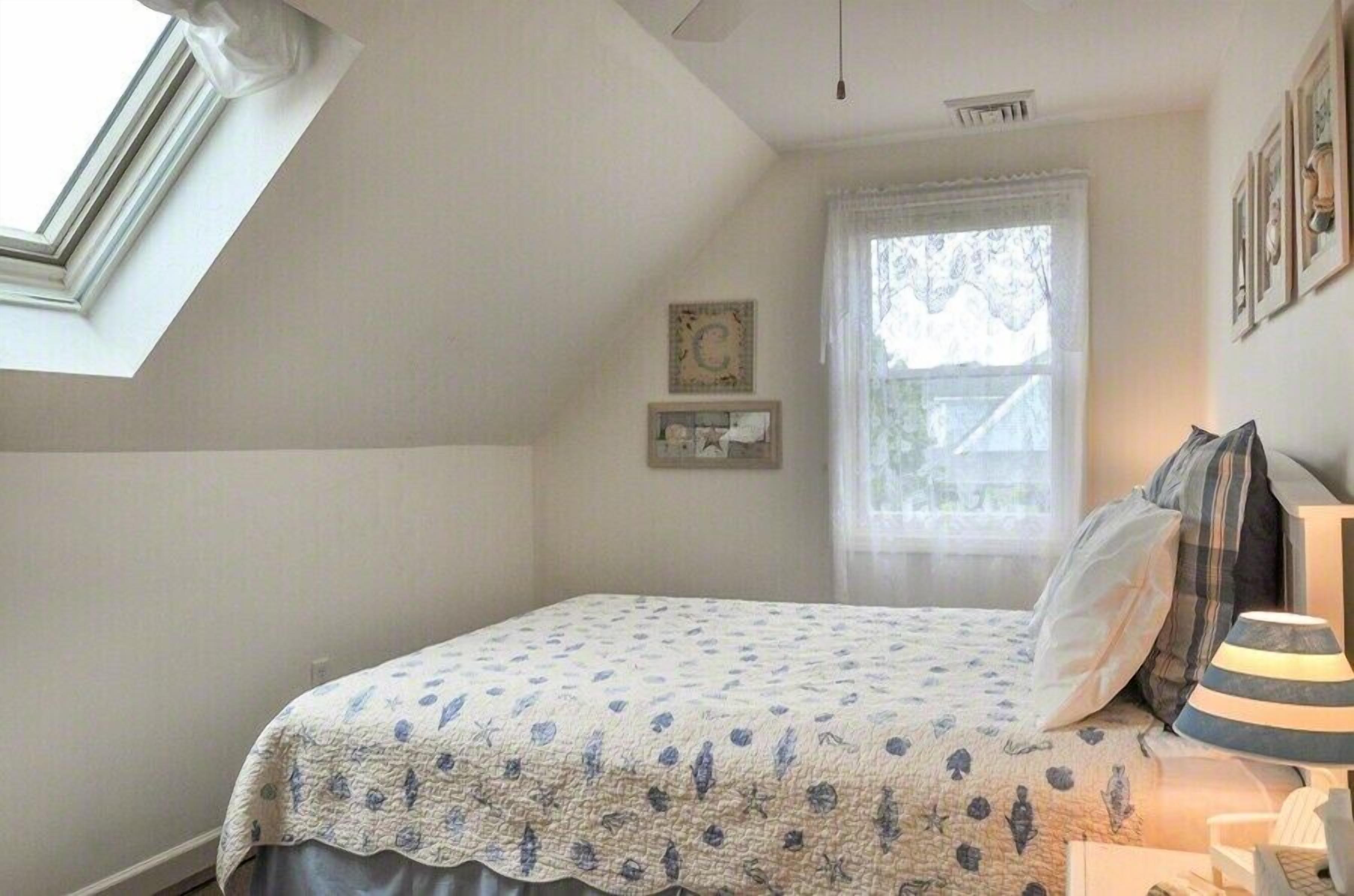 Ett sovrum med en säng, ett fönster och en lampa.