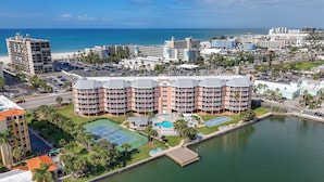 A hotel with multiple balconies, a swimming pool, and a view of the beach and ocean.