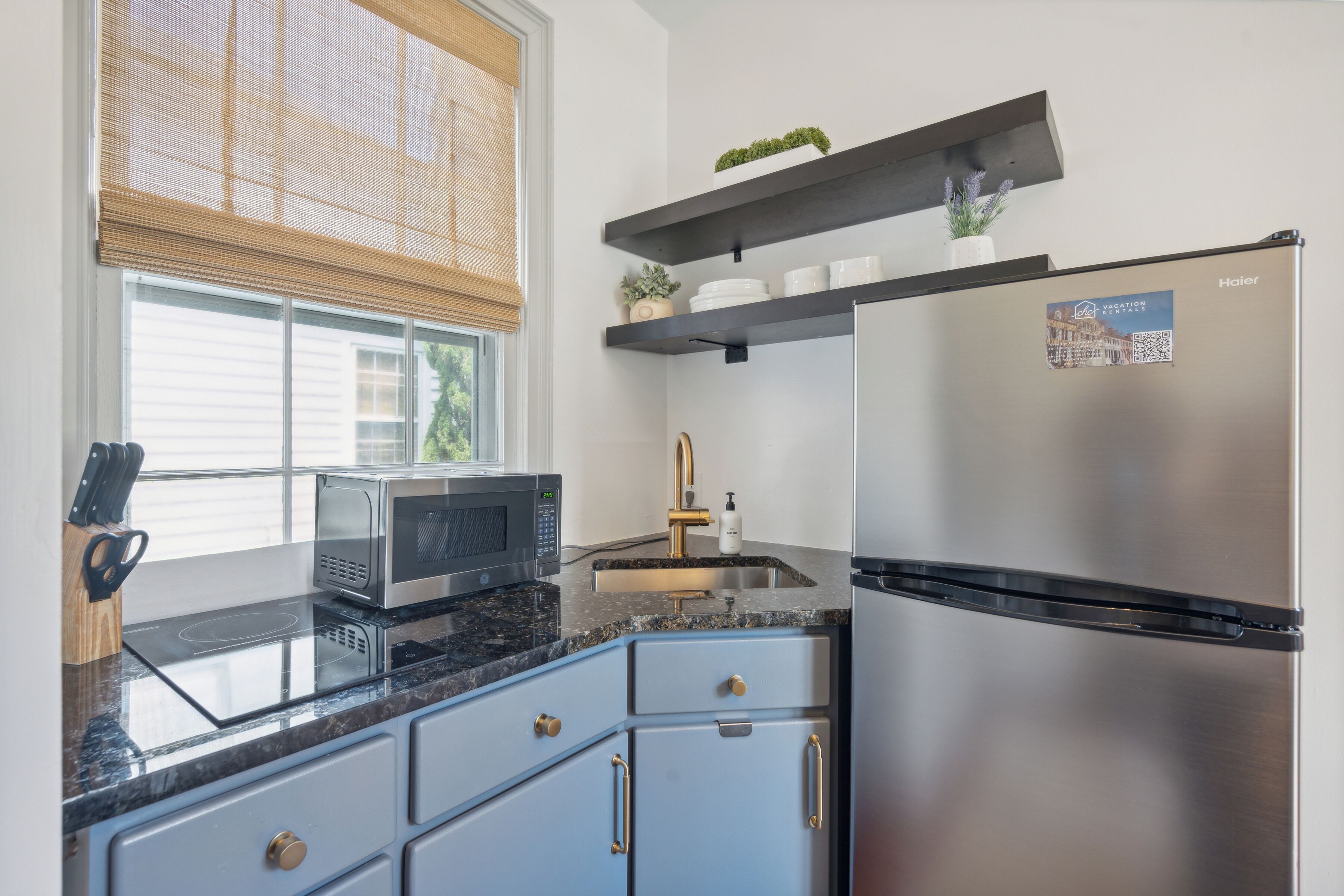Una cocina moderna con un refrigerador de acero inoxidable, un microondas, un lavaplatos y armarios azules.
