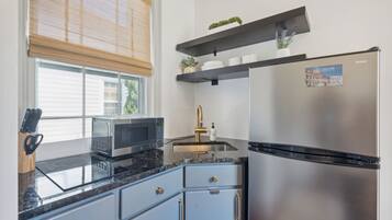 Una cocina moderna con un refrigerador de acero inoxidable, un microondas, un lavaplatos y armarios azules.