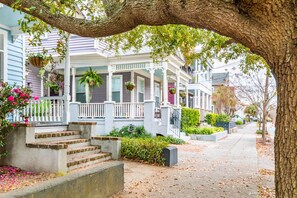 A row of townhouses with front porches, steps leading up to the entrance, and hanging flower baskets. - Spacious Apartment Downtown (Charleston)