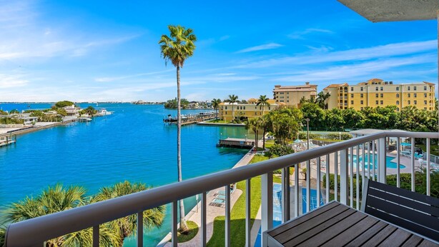 Un balcon avec vue sur un port de plaisance, une piscine et un bâtiment d’hôtel.
