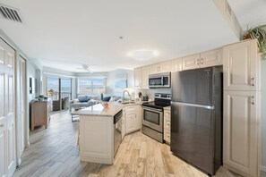 Enjoy cooking in the well-equipped kitchen with a central island, stainless steel appliances, and white cabinetry.