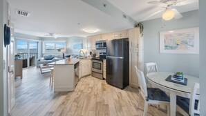 Una cocina moderna con armarios blancos, un refrigerador negro y un comedor con una mesa y sillas blancas.