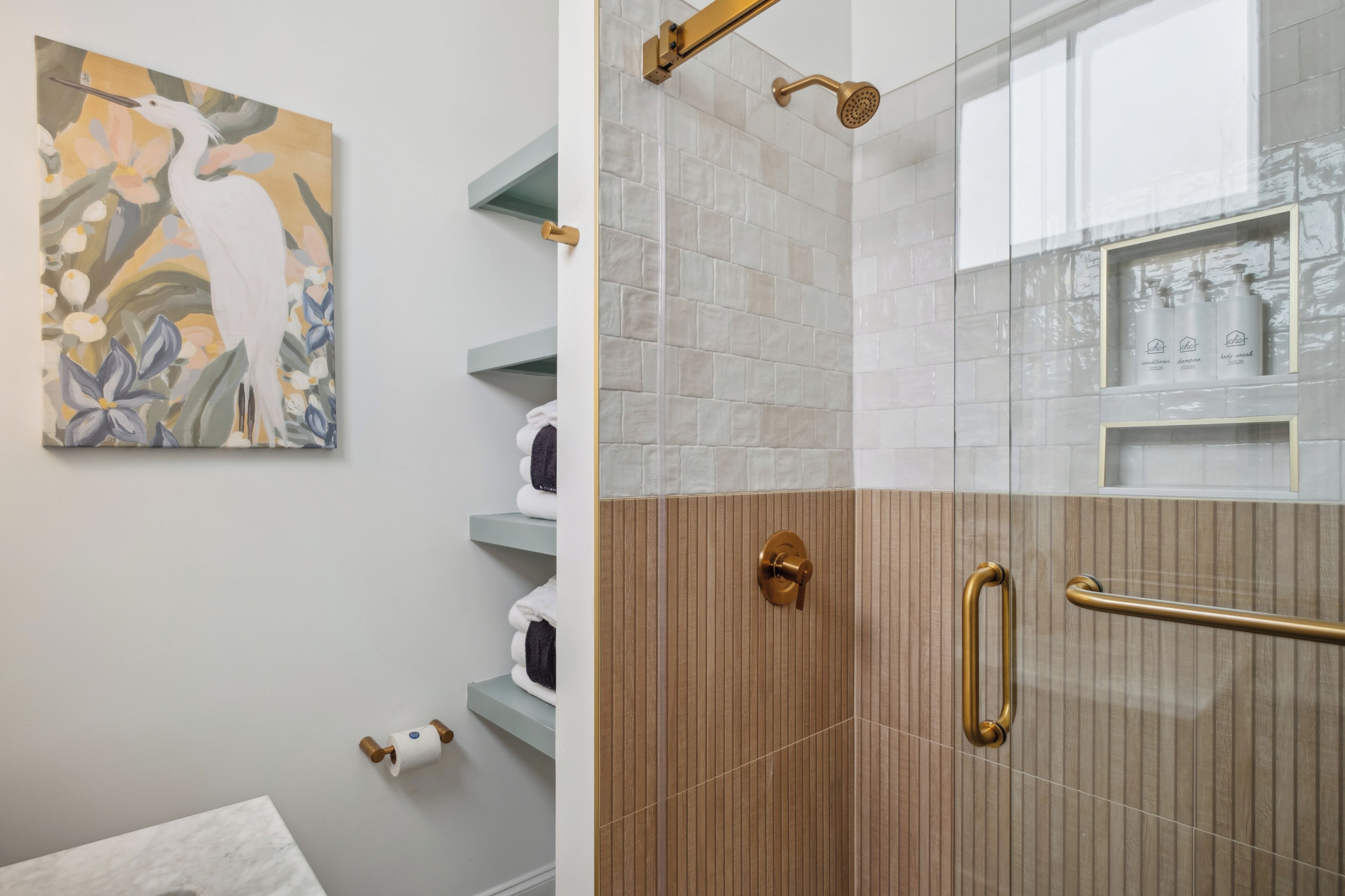 A modern bathroom with a glass shower enclosure, a wooden vanity, and a towel rack.