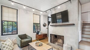 A living room with a fireplace, a sofa, a coffee table, and a TV mounted on the wall. - Revitalized Historical Southern Residence (Charleston)