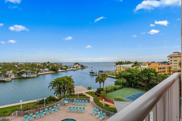 A resort with a pool, tennis court, and waterfront view.
