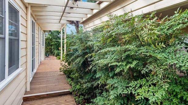 Una terraza cubierta de madera adyacente a un edificio con una pérgola.