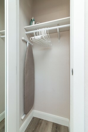 Um armário com um cabideiro, uma prateleira com uma garrafa e uma porta com uma toalha.