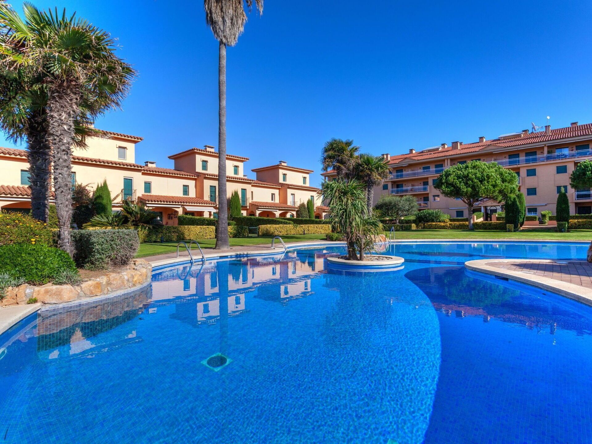 A resort with multiple swimming pools, palm trees, and Mediterranean-style buildings.