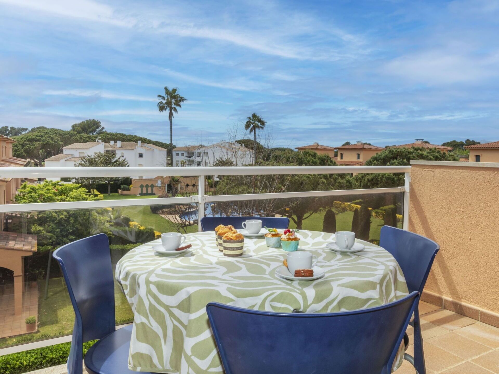 A balcony with a table set for two, overlooking a residential area with houses and greenery.