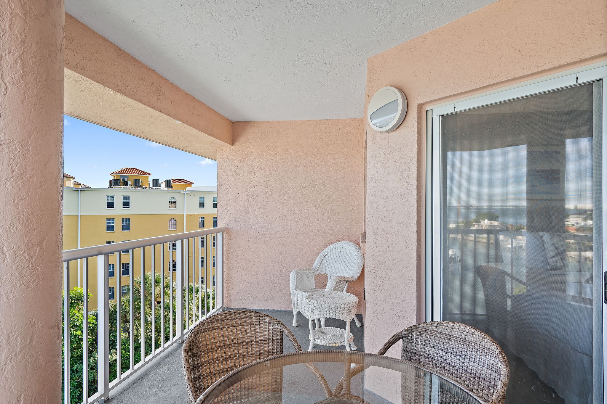 A balcony with wicker chairs, a small table, and a sliding glass door.