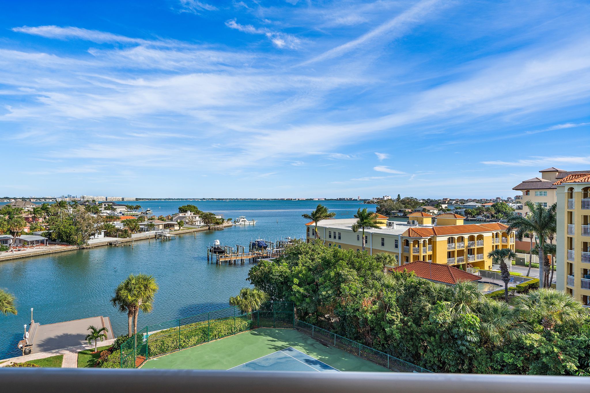 A waterfront property with a tennis court, marina, and residential buildings.