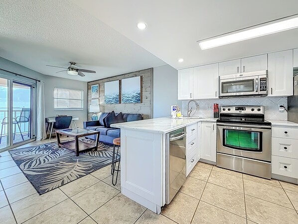 A modern kitchen with white cabinets, stainless steel appliances, and a large island.