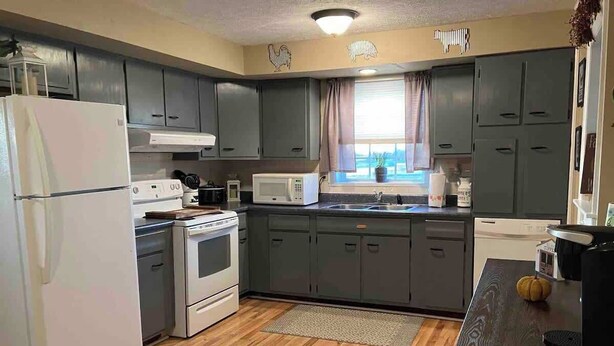 A compact kitchen with grey cabinets, a white refrigerator, a microwave, and a stove. - Beautiful Farmhouse near Lake Cumberland (Monticello)