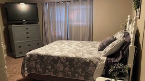 A bedroom with a bed, a dresser, a television, and a bedside table with a remote control. - Beautiful Farmhouse near Lake Cumberland (Monticello)