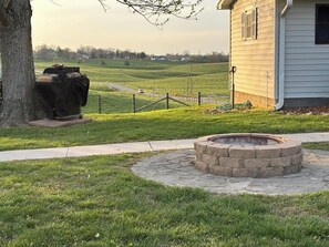 A stone fire pit in a circular stone structure, surrounded by a paved walkway. - Beautiful Farmhouse near Lake Cumberland (Monticello)