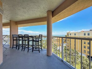 Un balcon avec une table et des chaises, une balustrade et une vue sur des bâtiments et l’eau.