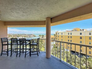 Un balcon avec une table et des chaises, offrant une vue sur le paysage urbain et l’étendue d’eau.