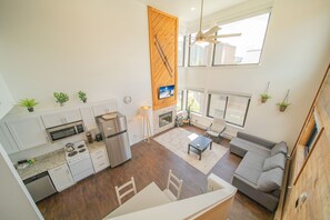 A modern kitchen with white cabinets, stainless steel appliances, and a wooden accent wall. - Mall 1423 (Keystone)