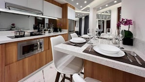A modern kitchen with a central island, white chairs, and a dining area with a table set for four.