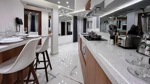A modern kitchen with a central island, bar stools, a built-in stove, and a variety of kitchen appliances.