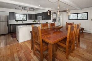 Una cocina moderna con armarios oscuros, electrodomésticos de acero inoxidable y una mesa de comedor de madera con sillas.