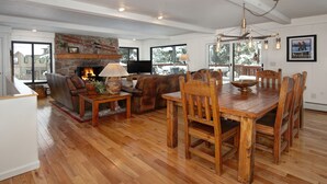 Een ruime woonkamer met een open haard, een houten eettafel en comfortabele zithoek.
