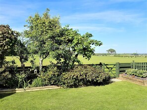 A grassy field with a wooden fence and trees.