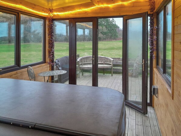 A room with a large bed, a small table, and chairs, with a view of a grassy area through glass doors.