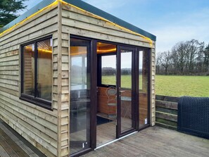 A wooden cabin with large glass doors, a wooden deck, and a view of a grassy field. - 1 bedroom accommodation in Annan, near Dumfries (Annan, near Dumfries)