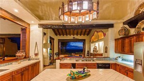A spacious kitchen with a large island, wooden cabinets, and a decorative ceiling light.