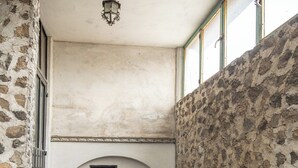Un baño rústico con paredes de piedra, suelo de madera, una bañera grande y una ventana pequeña con un marco de fotos.