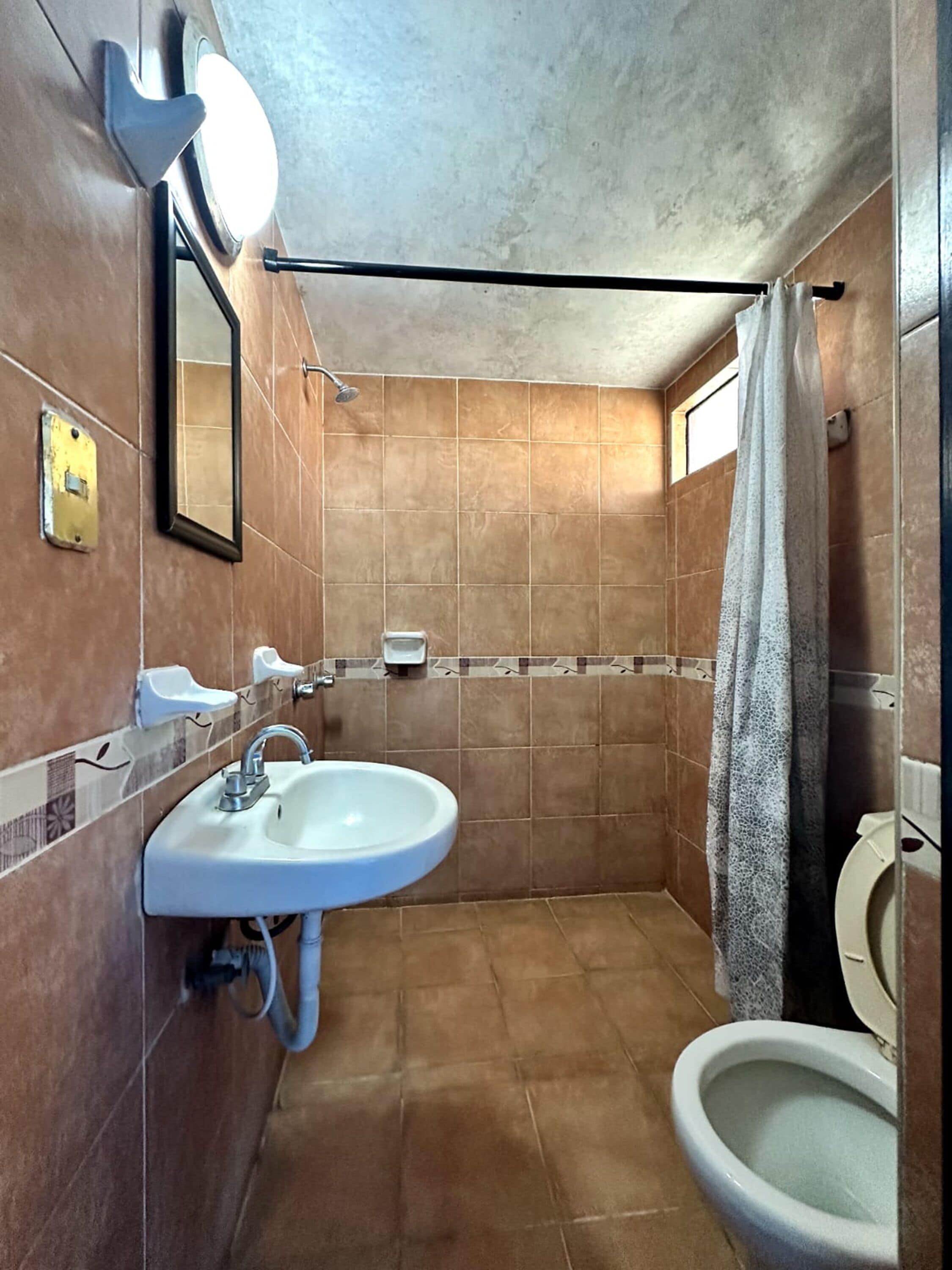 A small bathroom with a sink, mirror, and toilet.