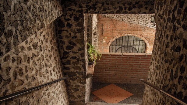Una escalera con paredes de piedra y una pared de ladrillo en la parte inferior.