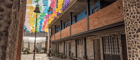 A narrow alleyway with a brick building, potted plants, and hanging decorations.