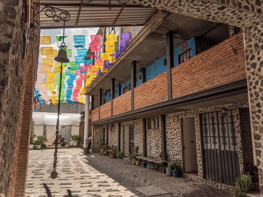 A narrow alleyway with a brick building, potted plants, and hanging decorations.