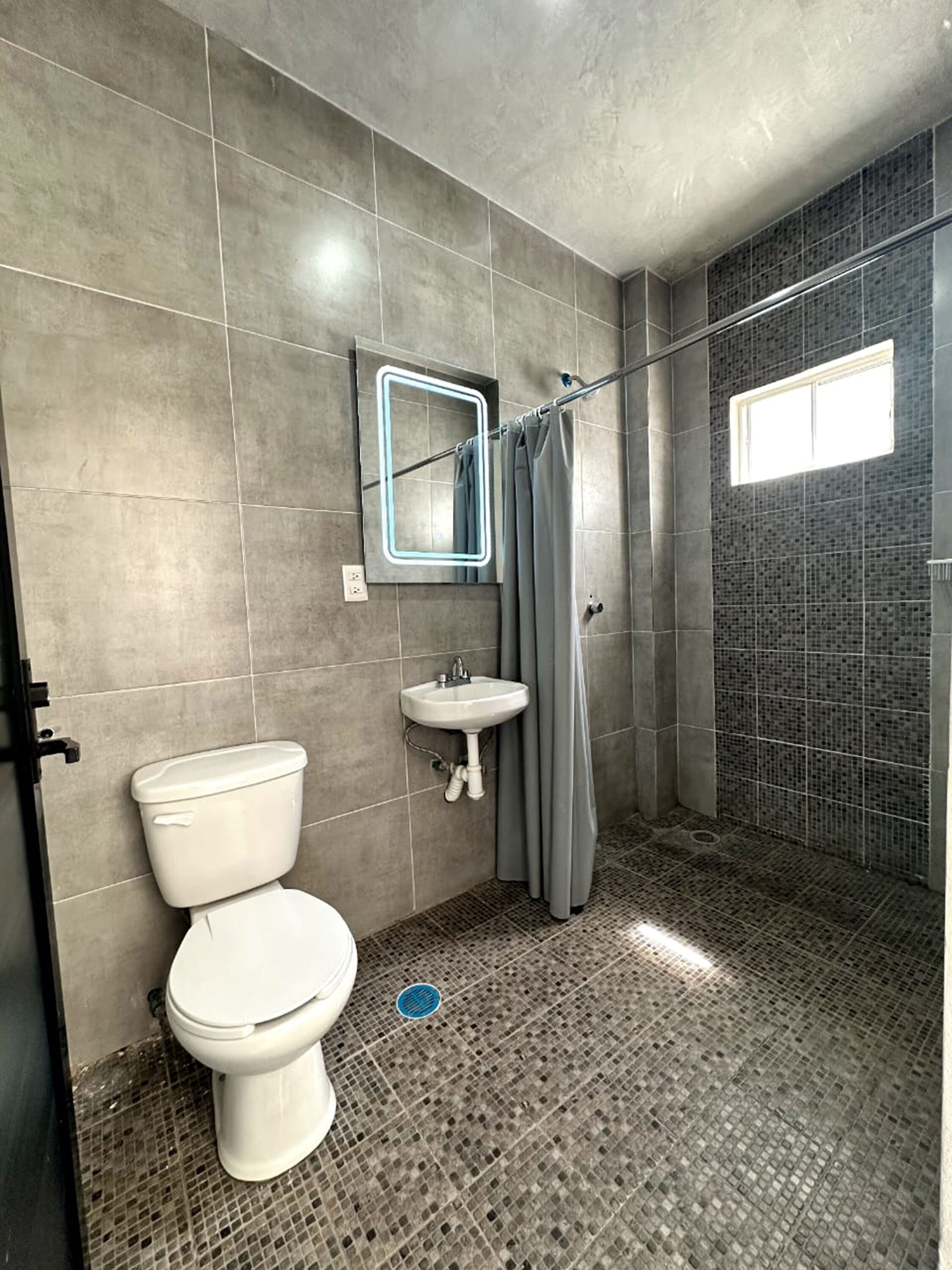 Un baño con inodoro, lavabo y zona de ducha.