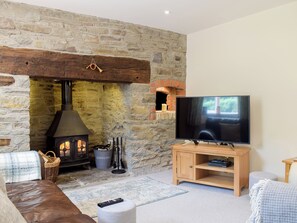 A cozy living room with a stone fireplace, a television, and a comfortable seating area.