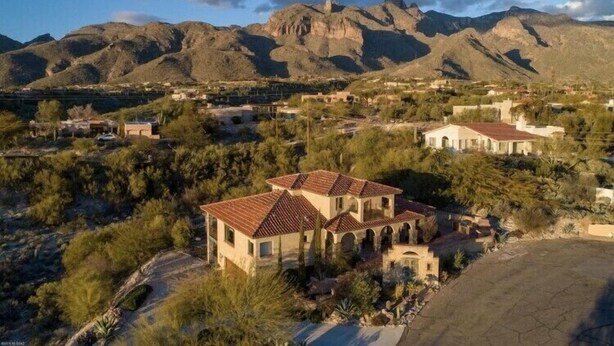 Un quartier résidentiel composé de maisons, dont certaines sont coiffées de toits en tuiles rouges, entouré de montagnes et d’une végétation clairsemée.