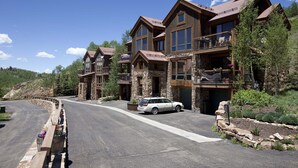 Un chalet à étages, doté d’une architecture en pierre et en bois, avec des balcons et de grandes fenêtres.