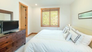 Une chambre à coucher avec un lit, un téléviseur posé sur une commode, une fenêtre donnant sur un beau paysage et une porte.