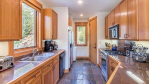 Une cuisine avec des meubles de rangement en bois, un lave-vaisselle, une cuisinière et un four à micro-ondes.