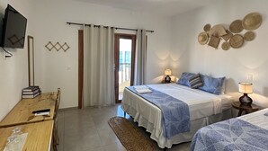 A hotel room with two beds, a desk, a TV, and a view of the outside. - Pousada Isabel (Jijoca de Jericoacoara)