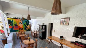 A spacious dining area with wooden tables and chairs, a refrigerator, and a television on the wall. - Pousada Isabel (Jijoca de Jericoacoara)